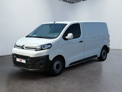 La camionnette blanche est garée dans une grande pièce équipée d'un ventilateur de plafond.