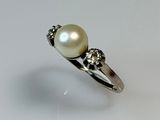 pearl and diamond ring on a white surface