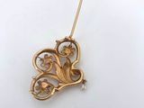 a close up of a gold brooch with flowers and leaves