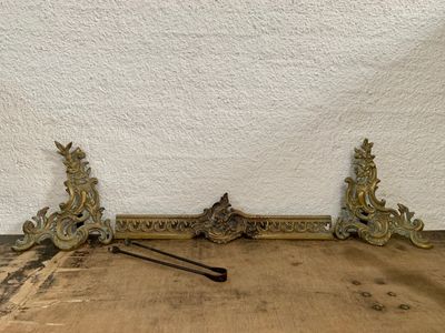 deux supports en laiton ouvragés posés sur une table en bois près d'un mur blanc