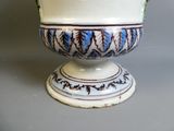 un vase blanc orné de motifs bleus et verts