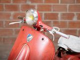 a red scooter that is parked in front of a brick wall