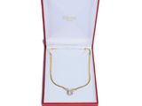 une boîte ouverte contenant un collier en or et un ruban rouge