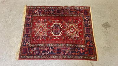 Le tapis posé au sol est rouge et bleu et comporte un motif.