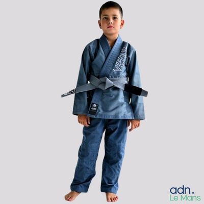 the boy is wearing a blue karate suit and holding a black belt