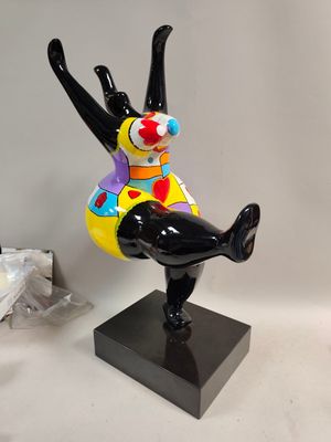 statue d'un clown assis sur un socle noir, sur fond blanc