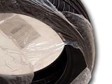a black tire wrapped in plastic on a white surface