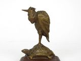 statue en bronze représentant un oiseau posé sur une tortue, sur un socle en bois