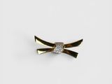 a close up of a gold and diamond bow brooch