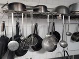 many pots and pans hanging from a rack in the kitchen