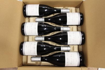 six bottles of wine in a cardboard box on a table