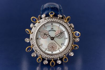 an image of a close up of a watch on a blue surface