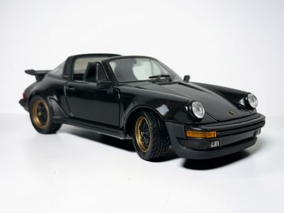 a black toy car that is sitting on a white surface