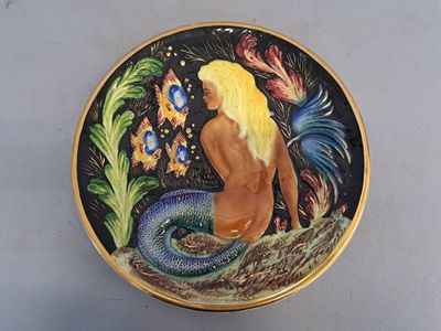 une photo d'une assiette décorative sur laquelle figure une sirène