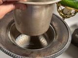 a person holding a silver cup on a silver plate