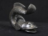 a silver statue of a fish on a black background