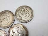 four different types of silver coins on a white surface