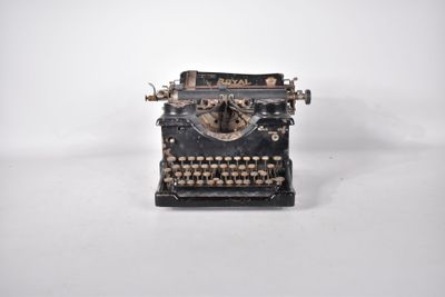 une vieille machine à écrire posée sur un plan de travail blanc