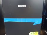 un réfrigérateur noir sur lequel est collé un autocollant, dans un parking