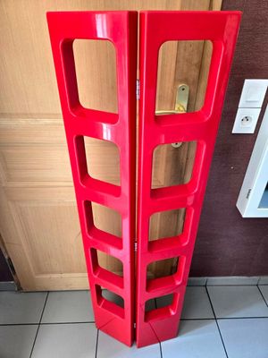 a red shelf that is on the floor in front of a door