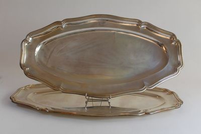 deux plateaux en argent posés l'un sur l'autre sur une table