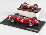 une maquette de voiture de course rouge posée sur un socle noir