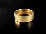 a gold wedding ring on a black surface