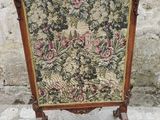 une vieille chaise dont le dossier est recouvert d'un tissu à motifs floraux et dont la structure est en bois