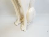 une statue représentant un chien blanc assis sur une surface blanche