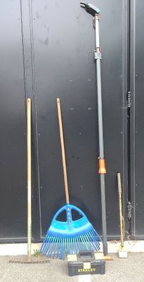 deux balais et un râteau devant la porte d'un garage