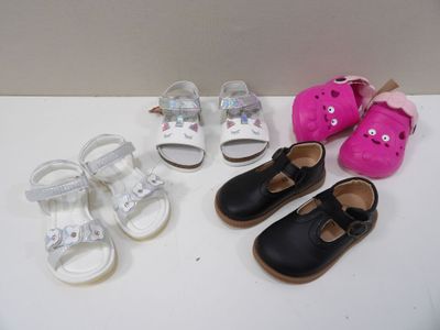 Plusieurs paires de chaussures pour bébé sont alignées sur une surface blanche