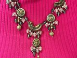 the woman is wearing a pink sweater and a necklace with beads on it