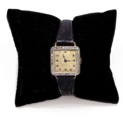 a black pillow with a gold watch on it