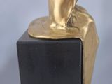 statue of a person sitting on a rock with a book in their hands