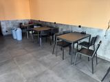 Des tables et des chaises sont alignées dans une pièce aux murs jaunes.
