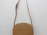 a tan leather purse hanging on a white wall