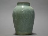 un vase vert posé sur une table, sur fond gris