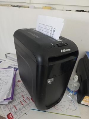 une déchiqueteuse noire posée sur un bureau, à côté d'une bouteille d'eau