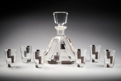 une carafe en verre entourée de nombreux verres à shot