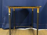 an image of a black and gold side table with a blue curtain in the background