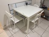 a white table and four chairs in a small kitchen