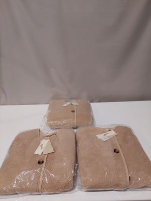 three bags of brown blankets sitting on top of a white table
