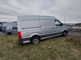 a van that is parked in the grass near a pile of wood