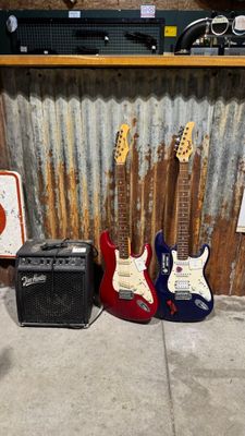 Des guitares et des amplis sont alignés devant un mur en tôle ondulée