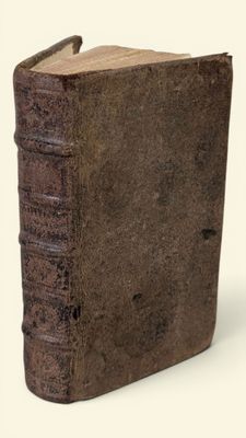 un vieux livre à la couverture brune posé sur une surface blanche