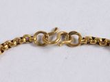 a close up of a gold chain bracelet on a white surface