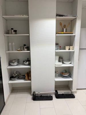 une petite cuisine équipée d'un réfrigérateur, d'un lave-vaisselle et d'un égouttoir à vaisselle