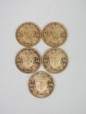 quatre pièces d'or ornées d'un blason, posées sur une surface blanche