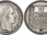 a silver coin with a woman ' s head and laurels on it