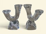 deux chandeliers en argent posés sur une surface blanche